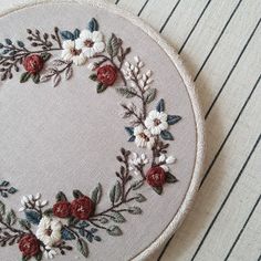 a close up of a embroidery on a piece of cloth with red and white flowers