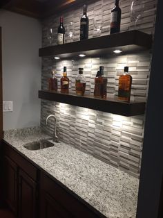 a kitchen with marble counter tops and shelves filled with liquor bottles on the wall next to a sink