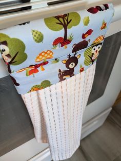 an oven mitt hanging from the side of a stove with owls and trees on it