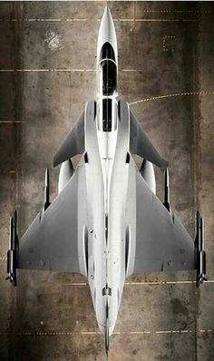 an aerial view of a fighter jet in the middle of a concrete floored area