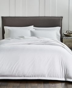 an image of a bed with white sheets and pillows in the middle, on top of a wooden floor