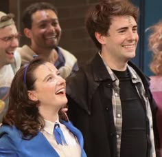 a group of people standing next to each other in front of a brick wall and smiling