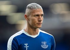 a close up of a soccer player wearing a blue uniform and looking off to the side