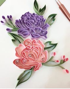 some paper flowers are sitting on a table next to scissors and pencils, with one flower cut out in the middle