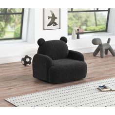 a black chair sitting on top of a hard wood floor next to a rug and window