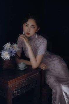 a woman sitting at a table with flowers in her hand