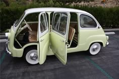 an old green and white car with its doors open