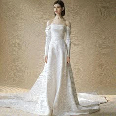 a woman in a white wedding dress with long sleeves and an off the shoulder neckline