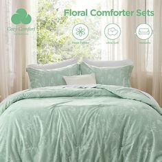 the comforter sets are light green with white flowers and leaves on it, along with matching pillows