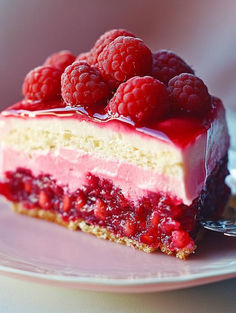 a piece of cake with raspberries on top is sitting on a pink plate