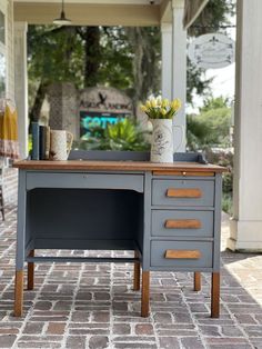 a gray desk with drawers and flowers on top