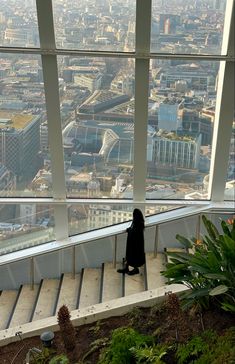 a woman sitting on top of a building looking out at the city from inside an observation tower