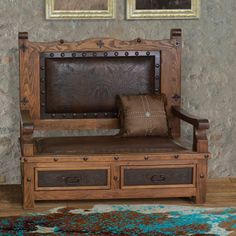 a wooden bench with two brown pillows on top of it next to a rug and framed pictures