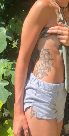 a woman with tattoos on her back standing in front of plants