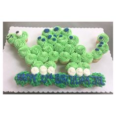 a green and white cake with cupcakes in the shape of a caterpillar