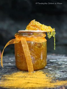 a jar filled with honey sitting on top of a wooden table next to a yellow ribbon