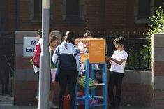 several people standing on the sidewalk near a sign