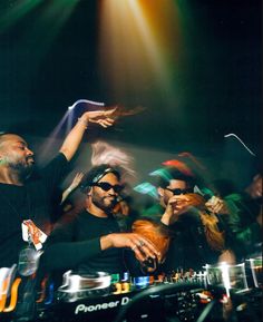 two djs at a party with their arms in the air and people behind them