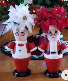 two ceramic figurines sitting on top of a wooden table next to a christmas tree