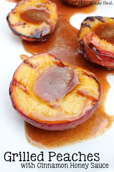 three cooked peaches on a white plate with syrup drizzled around them