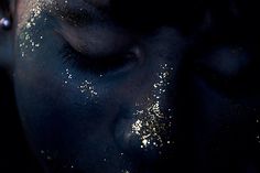 a woman with black and white makeup has glitter on her face as she looks into the camera