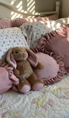 a stuffed rabbit sitting on top of a bed next to pillows and pillowcases