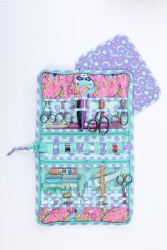 an open purse with scissors and other items in it sitting on a table next to a white wall