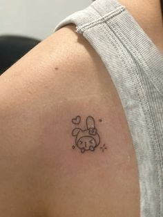 a small tattoo on the back of a woman's shoulder, depicting a dog with a heart in its mouth