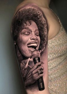 a black and white photo of a woman singing into a microphone tattoo on the arm