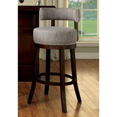 an upholstered bar stool sits in front of a window and wooden flooring