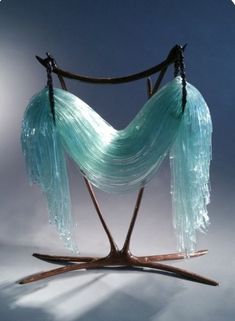 a sculpture made out of glass and wooden sticks with long, flowing streamers hanging from it's sides