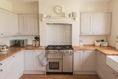 a kitchen with white cabinets and wood counter tops, an oven, dishwasher and sink