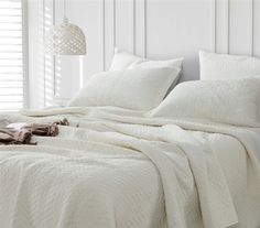 an unmade bed with white sheets and pillows