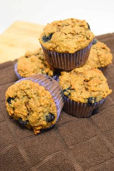 blueberry muffins sitting on top of a brown cloth