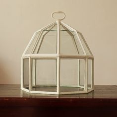 a small white glass lantern sitting on top of a wooden table