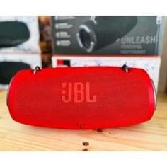 a red jbl speaker sitting on top of a wooden table