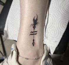 a woman's foot with a small tattoo on the ankle and an arrow in the middle