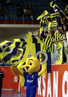 a mascot waving at the crowd in front of him with his hand up and other fans behind him