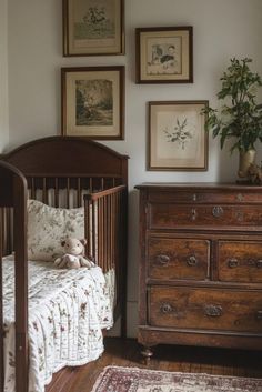 a baby crib with a teddy bear in it next to a dresser and pictures on the wall