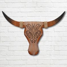 a wooden bull's head mounted on a white brick wall with intricately carved horns