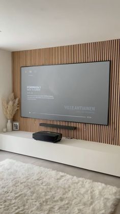 a flat screen tv mounted to the side of a wall in front of a white rug