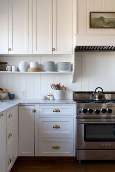 a stove top oven sitting inside of a kitchen next to white cupboards and drawers