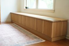 an empty room with a rug, window and wooden paneling on the floor in front of it