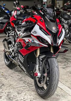 a red and black motorcycle parked in front of other motorcycles