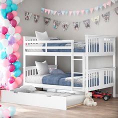 a white bunk bed sitting in a bedroom next to a pile of pillows and balloons