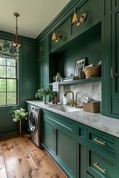 a kitchen with green cabinets and marble counter tops, gold pulls on the faucet