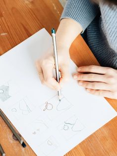 a person writing on paper with a pen