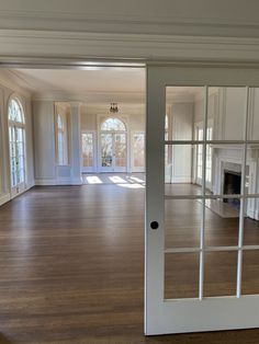 an empty living room with hard wood floors and white painted walls, large glass doors open to the dining area