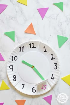 a paper plate with a clock on it and some colored confetti around it