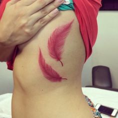 a woman's stomach with red feathers painted on it